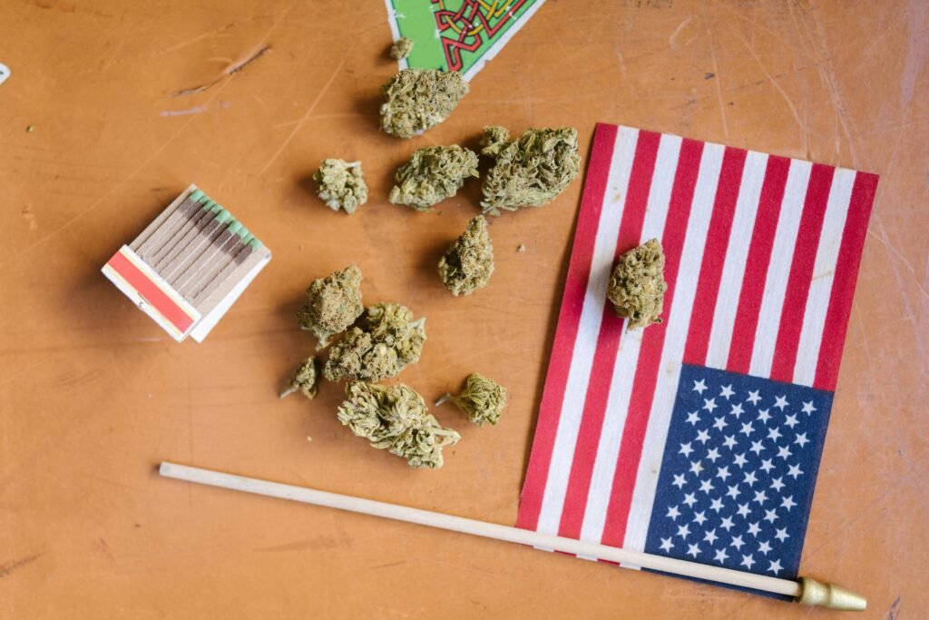 Top view of cannabis buds, matchsticks, and American flag on a wooden table.